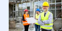 A smiling construction foreman in front of a building site