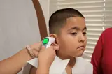 Nurse obtains a boy's temperature