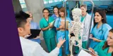 A group of smiling healthcare professionals examining a skeleton model