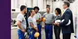 A team with hardhats talking to two people in suits